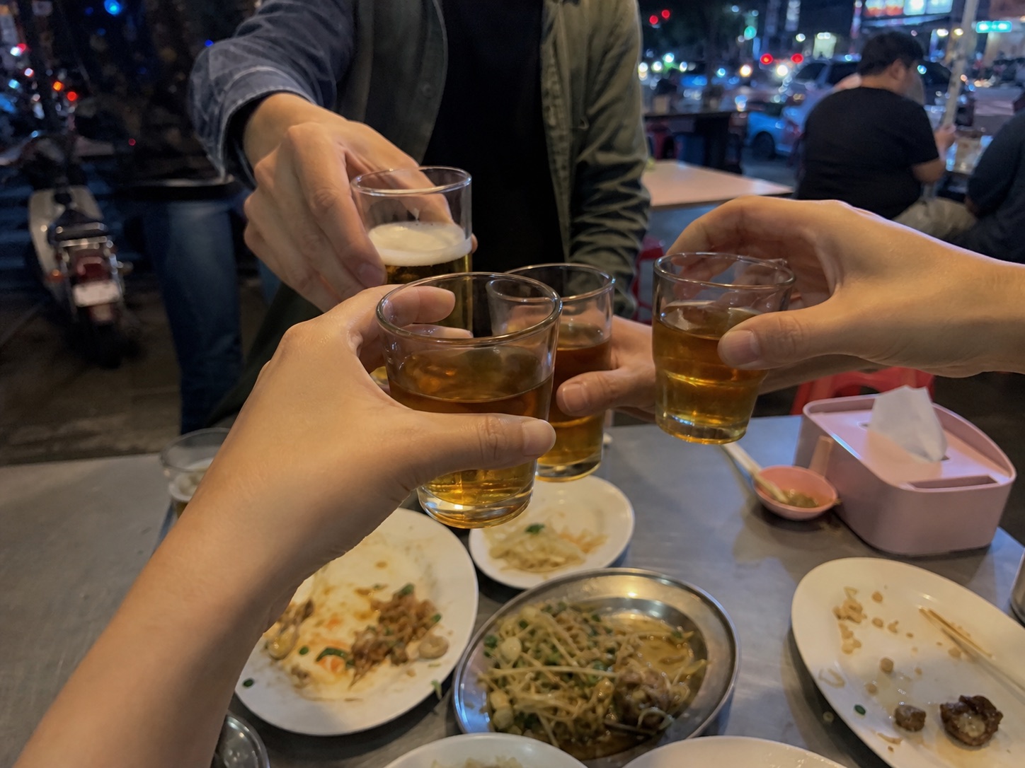 熱炒桌邊朋友碰杯與城市夜晚的氣氛影像